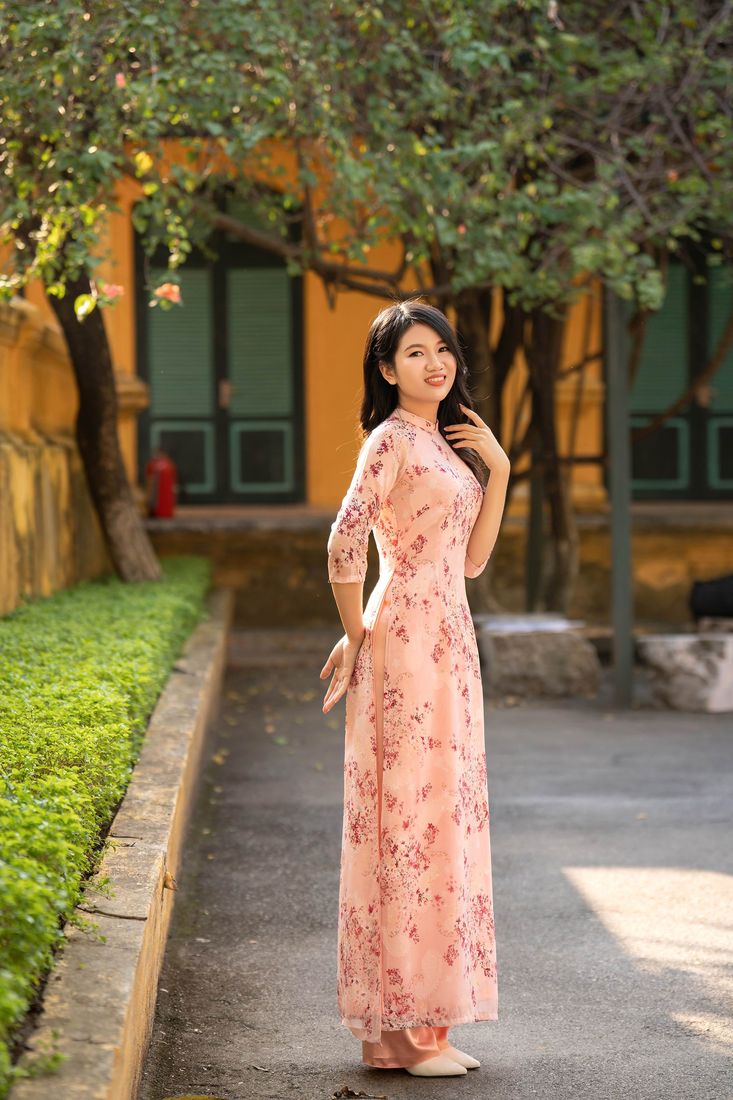 Áo dài hồng phấn trên lối đi vườn tường vàng — Thúy Tô Studio